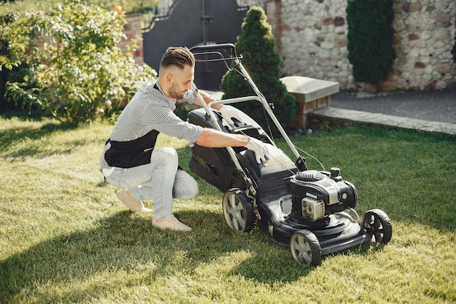 A tenant attaches a bag to their lawnmower before mowing the lawn